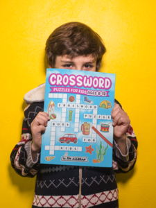 Boy holding Crossword Puzzle Book for Kids ages 8-12 by Jim Allbran